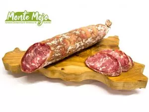 Salame Monte Mojo intero e affettato su tagliere.